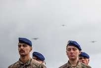 French service members stand in formation as C-130 Hercules aircraft fly overhead during a D-Day commemorative ceremony near Omaha Beach, Normandy, France, June 6, 2025. The event marked the 81st anniversary of the Allied landings and honored the enduring partnership between France and the United States. (U.S. Army photo by Sgt. Tyler Brock)