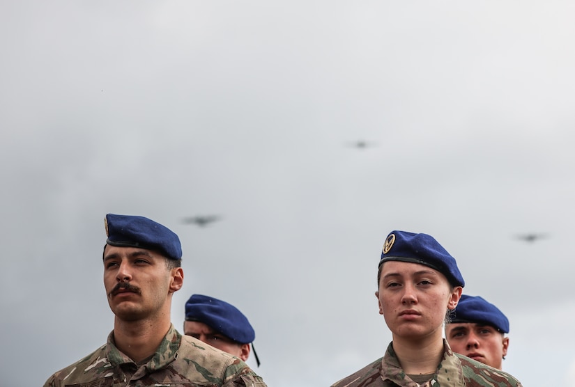 French service members stand in formation as C-130 Hercules aircraft fly overhead during a D-Day commemorative ceremony near Omaha Beach, Normandy, France, June 6, 2025. The event marked the 81st anniversary of the Allied landings and honored the enduring partnership between France and the United States. (U.S. Army photo by Sgt. Tyler Brock)