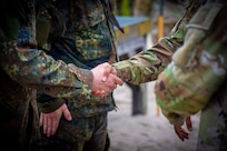 A Bundeswehr Soldier shakes hands with a U.S. Army Soldier while attending the 7th Army Noncommissioned Officer Academy (NCOA), Grafenwoehr, Germany,  June 5, 2025.
