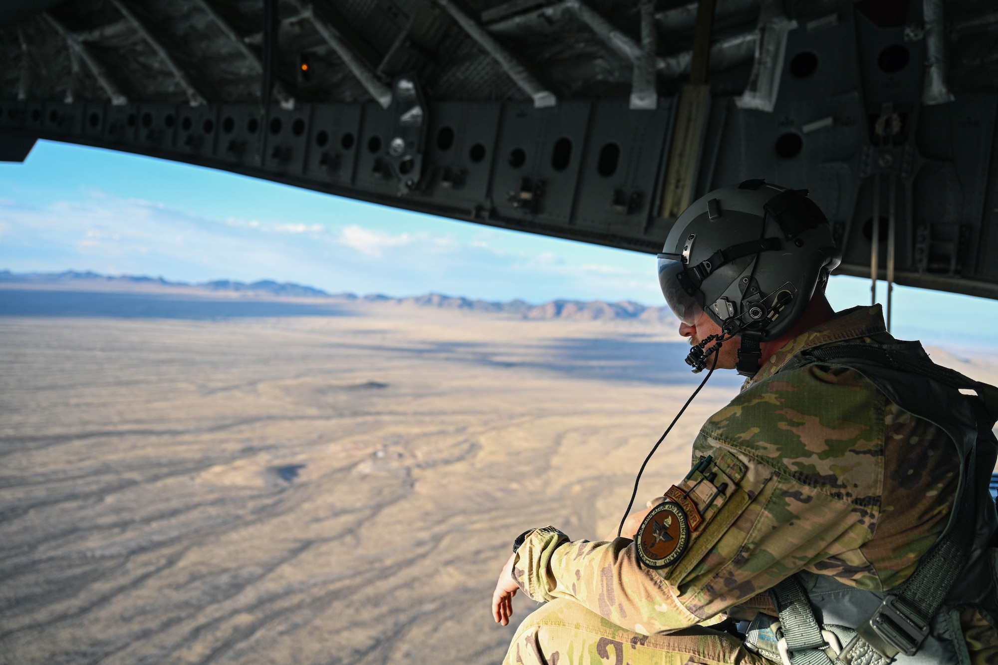 U.S. Air Force Tech. Sgt. Alex Green, 97th Training Squadron evaluator loadmaster and Air Education and Training Command master instructor, sits on the ramp of a C-17 Globemaster III mid-flight over Nevada, May 28, 2025. The C-17’s airdrop capabilities enable rapid delivery of personnel, vehicles, and supplies to austere environments during joint operations. (U.S. Air Force photo by Airman 1st Class Jonah Bliss)