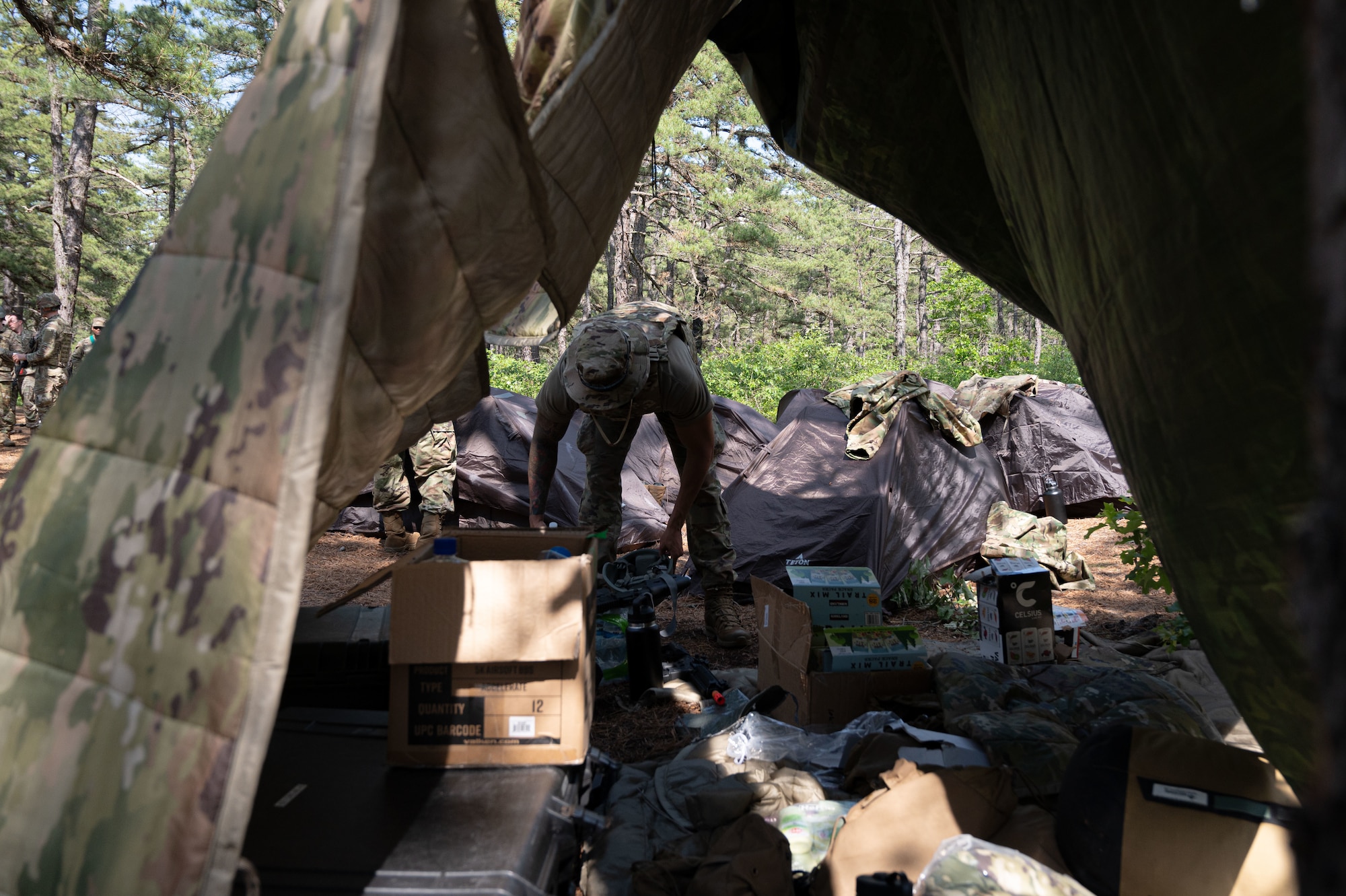 A U.S. Air Force Airman attending the Kish Airman Leadership School sorts through supplies at a bivouac site.