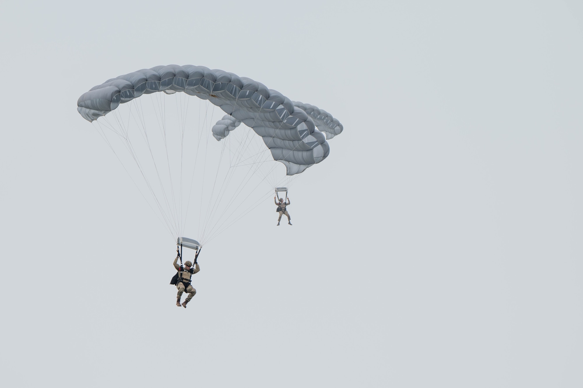 Pararescue specialists descend toward the drop zone