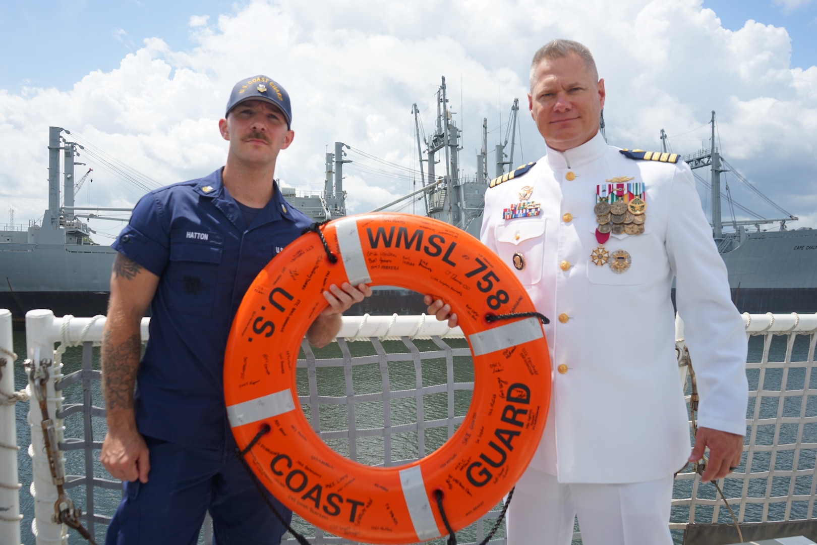 Capt. Jonathan Carter, commanding officer of Coast Guard Cutter Stone (WMSL 758), and Petty Officer 1st Class Lucas Hatton, a crew member assigned to Stone, pose for a photo with Carter's going away gift following the cutter's change-of-command ceremony in North Charleston, South Carolina, June 5, 2025. The change-of-command ceremony is a time-honored tradition that formally demonstrates the continuity of authority within a command, conducted before the assembled crew and honored guests. (U.S. Coast Guard photo by Ensign Sarah Pearson)