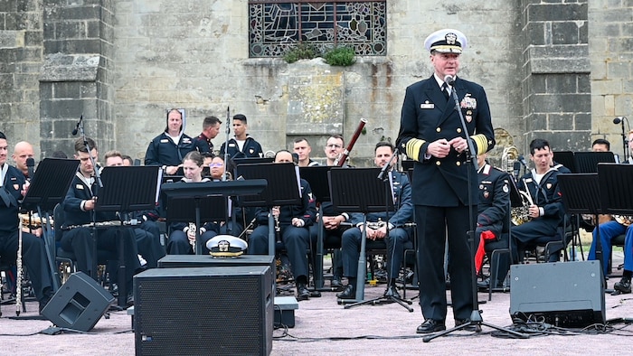 dm. Stuart B. Munsch, commander of U.S. Naval Forces Europe (NAVEUR), speaks to a crowd of military members, veterans and civilians at Sainte-Mère-Église Church in Sainte-Mère-Église, France during the United in Our Victory NAVEUR Band concert.