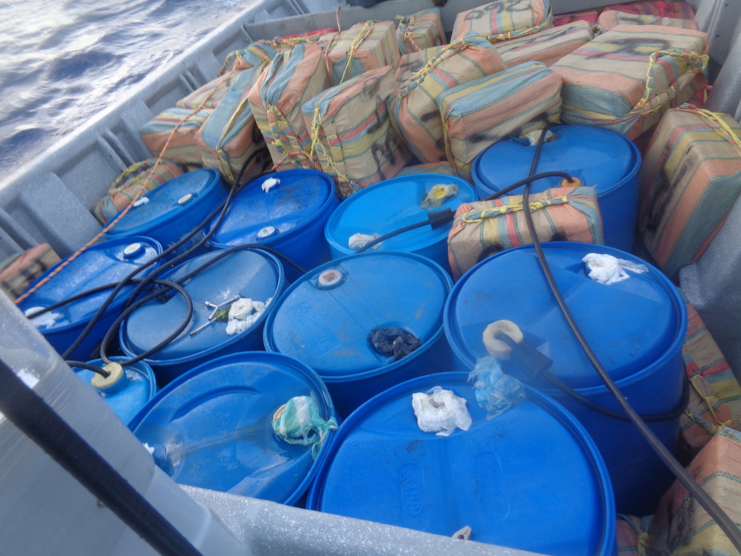 Bales and barrels of illicit drugs await to be taken aboard a Coast Guard cutter