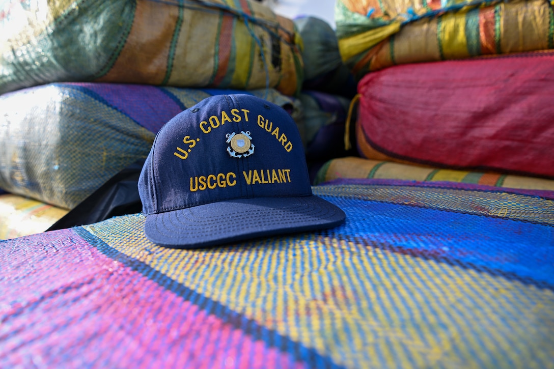 A Coast Guard hat sits on bales of drugs