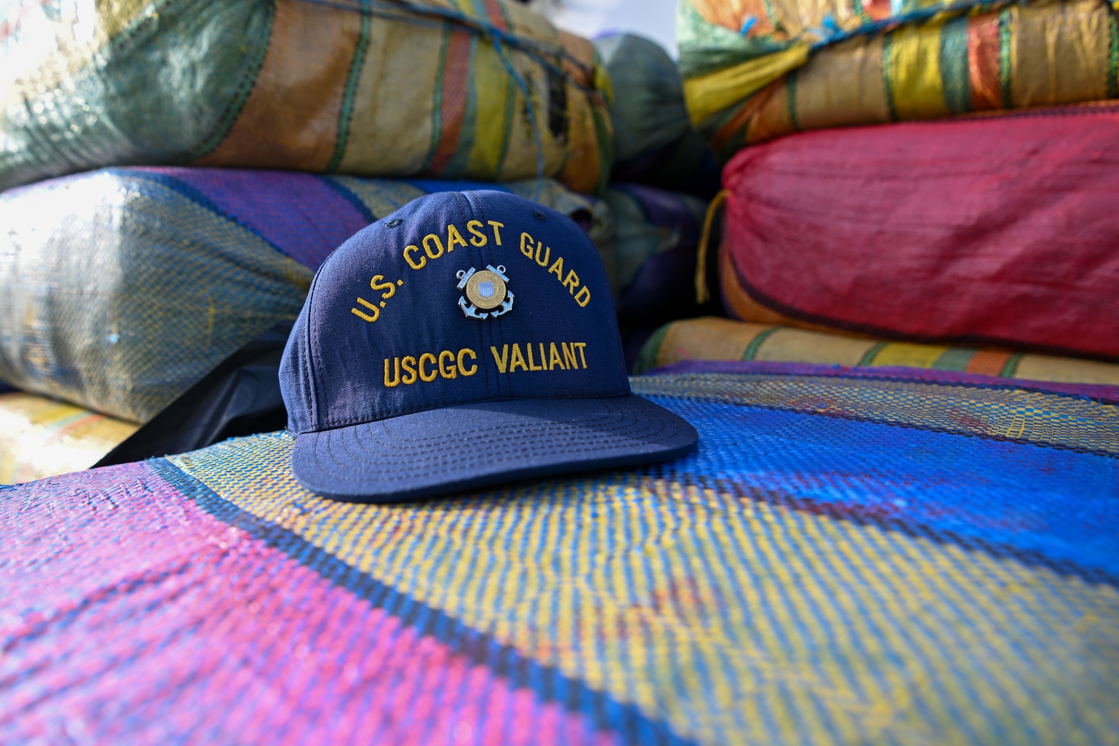 A Coast Guard hat sits on bales of drugs