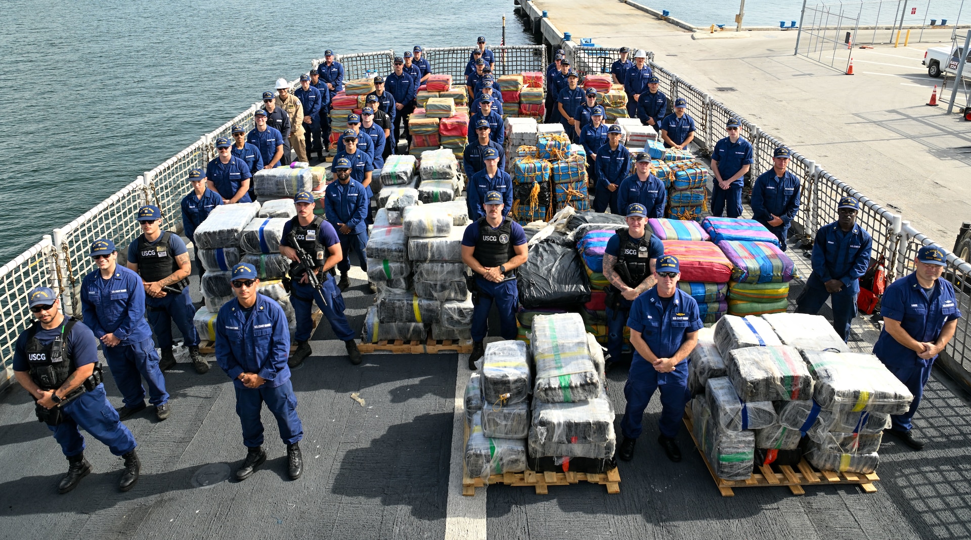 USCGC Valiant (WMEC 621) crew stands next to bales of drugs