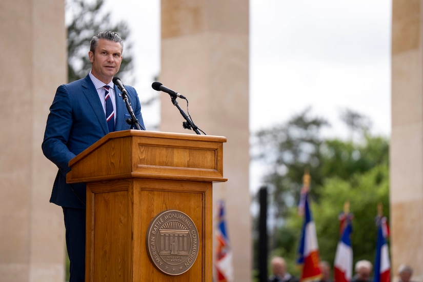 A man speaks at a podium outside on a sunny day.