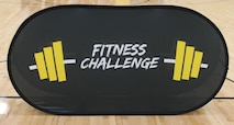 A “Fitness Challenge” banner stands at center court during a U.S. Army Fitness Challenge event at a Kansas City-area high school, May 2025. The challenge promotes physical fitness, teamwork, and Army values among high school students.