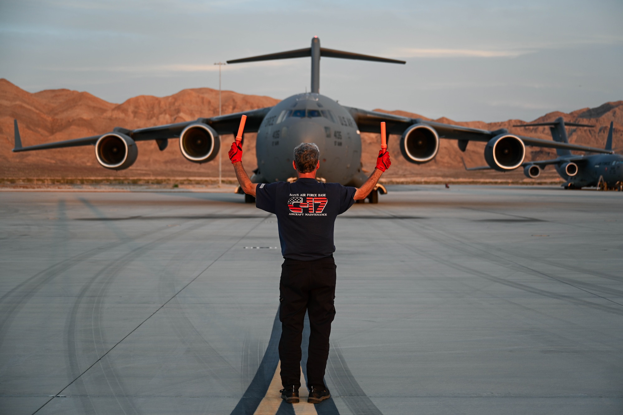 James Daugherty, 97th Aircraft Maintenance Squadron C-17 dedicated crew chief, marshals in a C-17 Globemaster III aircraft at Nellis Air Force Base, Nevada, May 28, 2025. Crew chiefs accompany missions to ensure the aircraft remains operationally capable. (U.S. Air Force photo by Airman 1st Class Jonah Bliss)