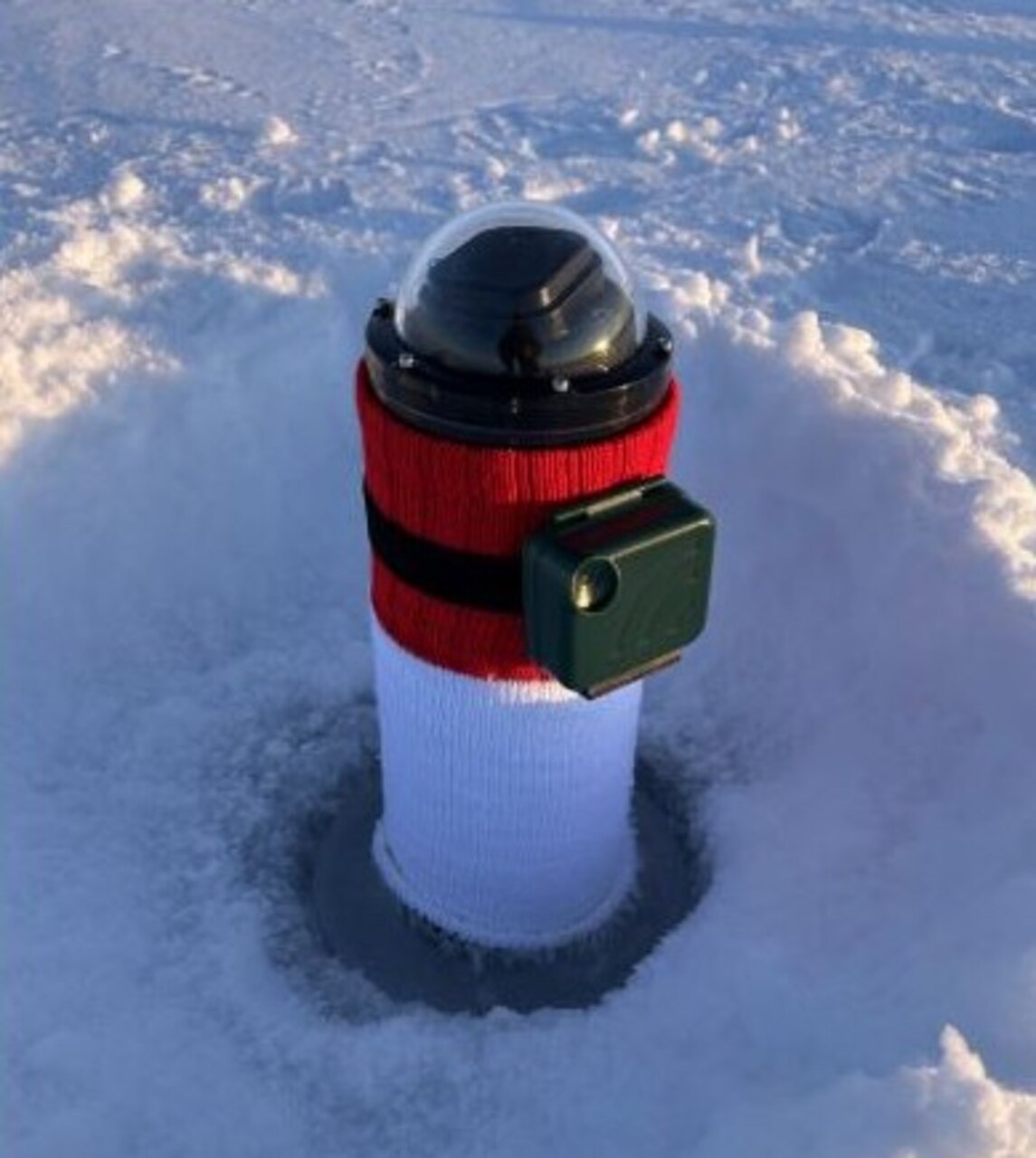Inserted into a hole in sea ice, the cryophone on the right is frozen in place. Attached around its protective sleeve is a microphone. (Courtesy photo from Benjamin Reeder)
