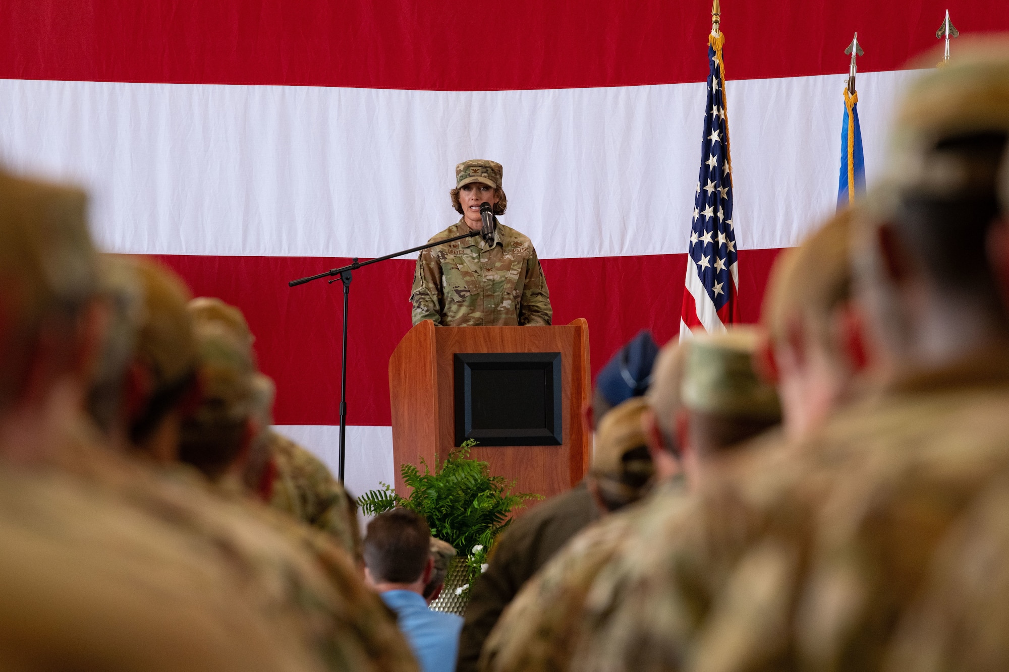 a military commander addresses formations of airmen on a stage
