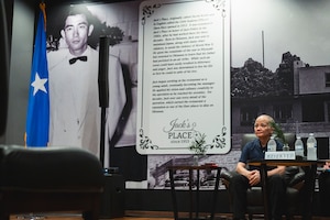 Hiko Oshiro, Kadena Air Base Officers Club Manager, sits next to a photo of his father, Sadamu “Jack” Oshiro, in the Officers Club during a dedication ceremony at Kadena Air Base, Japan, June 6, 2025.