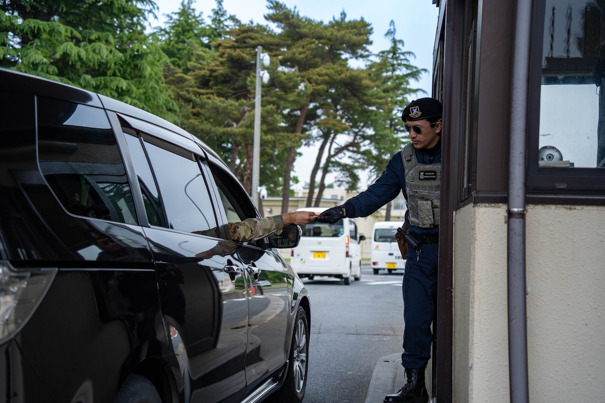 A U.S. Air Force Civilian Guardsmen CG assigned to the 35th Security Forces Squadron, guards the main gate and checks a member’s identification at Misawa Air Base, Japan, June 4, 2025