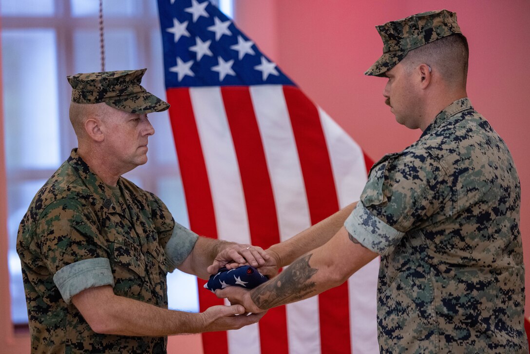 U.S. Marine Corps Master Sgt. Daniel Brewer, left, the operations chief with Headquarters Battalion, 2d Marine Division, receives the colors during his retirement ceremony at Marston Pavilion on Marine Corps Base Camp Lejeune, North Carolina, May 29, 2025. The ceremony was held to honor Master Sgt. Brewer’s 29 years of faithful dedication to service. (U.S. Marine Corps photo by Cpl. Noelia Vazquez)
