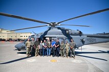 Airmen and civilians pose in front of an MH-139A helicopter