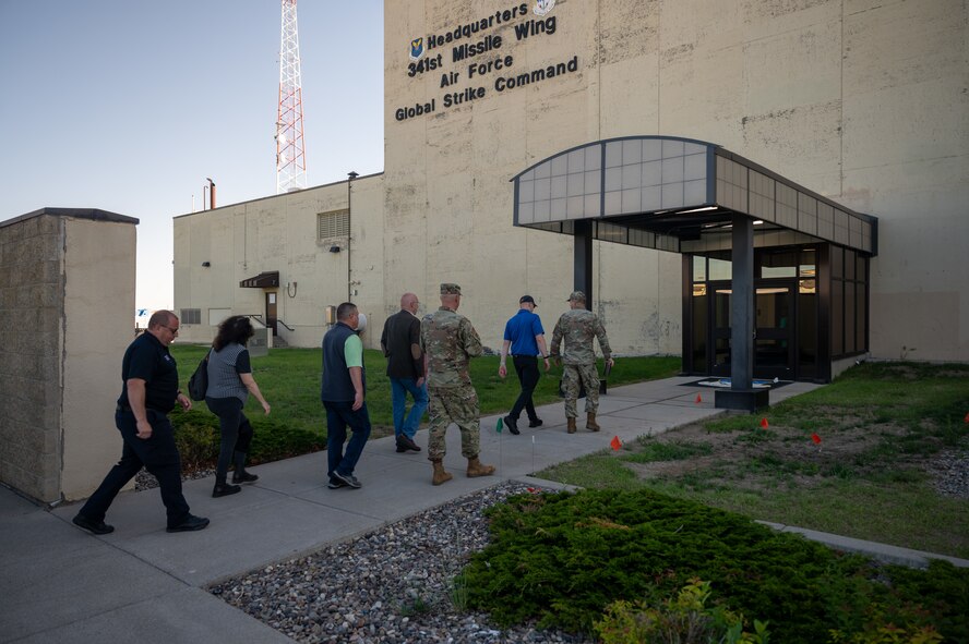 Airmen and civilians walk into a building