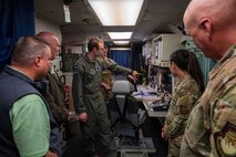 Two Missileers point at a launch console while two civilians and two Airmen watch