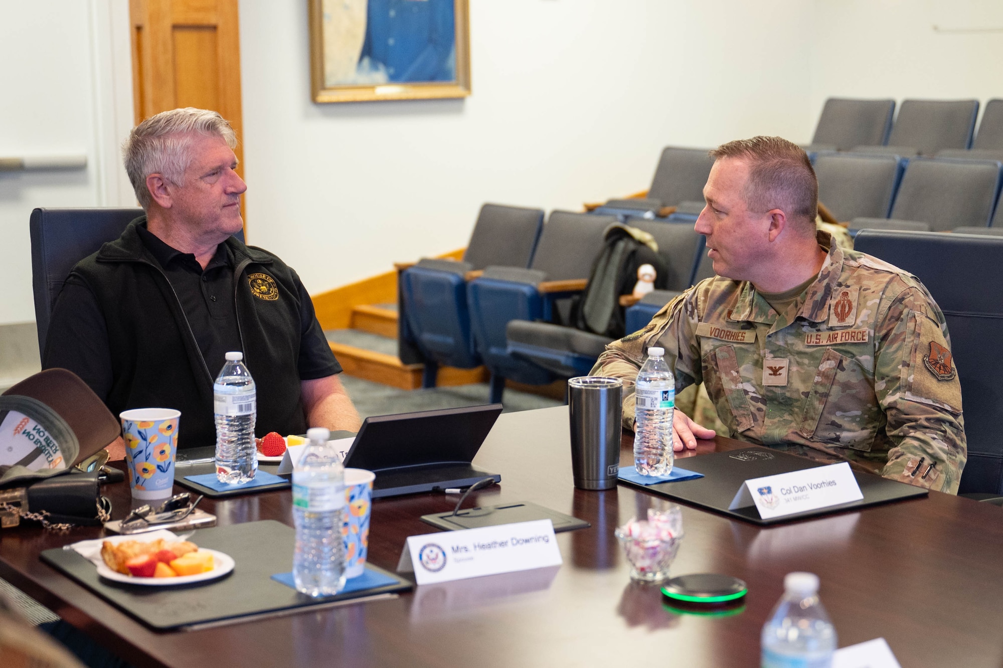 A civilian and an Airman sitting at a table talking to each other