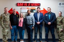 People posing in front of a digital clock