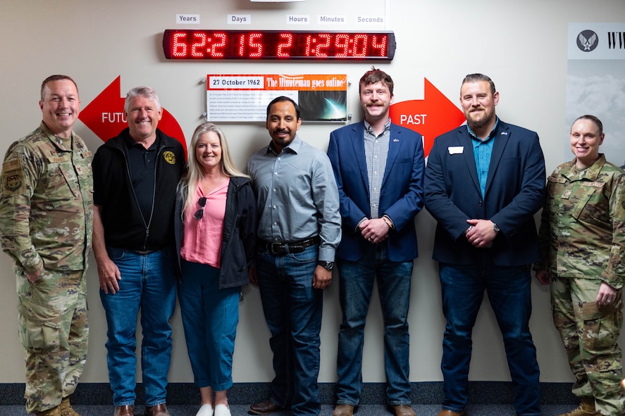 People posing in front of a digital clock