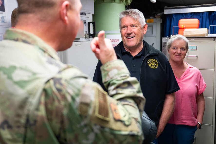 two civilians looking towards an Airman
