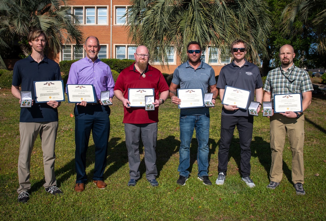 Members from the NSWC PCD Standoff Target Reacquire Identify Detection Expeditionary Navigation Tool (STRIDENT) Program receive the Navy Civilian Service Achievement Medal for enhancing warfighter capabilities, April 18, 2025. (from left) David Trexler, Dr. John Kelly, Steven Roberts, Aaron Burghardt, Joshua Lowe, Jonathan Outlaw, and Christine Livingston (not pictured). (U.S. Navy photo by Anthony Powers)
