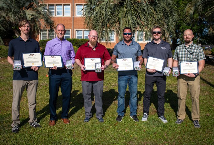 Members from the NSWC PCD Standoff Target Reacquire Identify Detection Expeditionary Navigation Tool (STRIDENT) Program receive the Navy Civilian Service Achievement Medal for enhancing warfighter capabilities, April 18, 2025. (from left) David Trexler, Dr. John Kelly, Steven Roberts, Aaron Burghardt, Joshua Lowe, Jonathan Outlaw, and Christine Livingston (not pictured). (U.S. Navy photo by Anthony Powers)