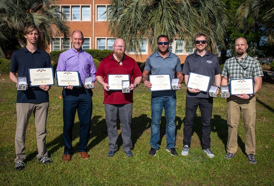 Members from the NSWC PCD Standoff Target Reacquire Identify Detection Expeditionary Navigation Tool (STRIDENT) Program receive the Navy Civilian Service Achievement Medal for enhancing warfighter capabilities, April 18, 2025. (from left) David Trexler, Dr. John Kelly, Steven Roberts, Aaron Burghardt, Joshua Lowe, Jonathan Outlaw, and Christine Livingston (not pictured). (U.S. Navy photo by Anthony Powers)