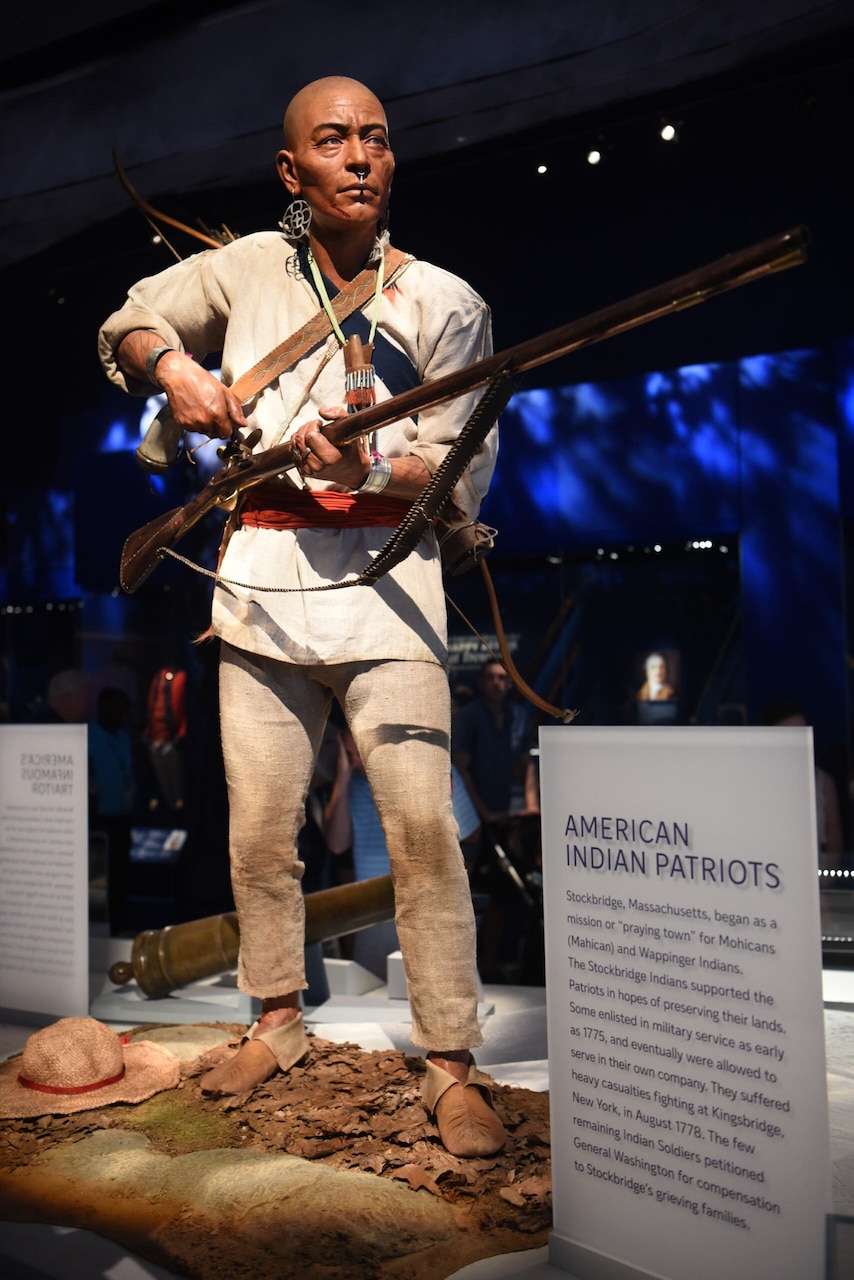 A mannequin in Indian clothing is shown loading a rifle while on display at a museum.