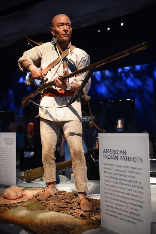 A mannequin in Indian clothing is shown loading a rifle while on display at a museum.