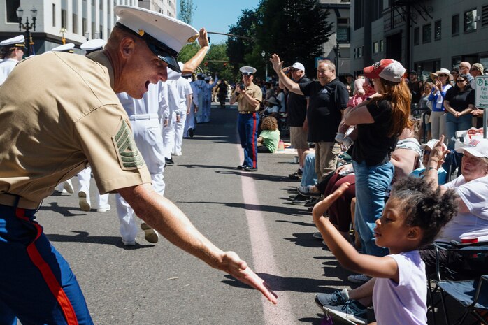 PORTLAND, OREGON (June 7, 2025) – U.S. Marine Corps 1st Sgt. Lloyd Crabtree, the senior enlisted leader for First Intelligence Battalion, I Marine Expeditionary Force Information Group, and a native of California, interacts with Portland natives at the Grand Floral Parade during Portland Fleet Week, June 7, 2025. Portland Fleet Week is a time-honored celebration of the sea services and provides an opportunity for the citizens of Oregon to meet Sailors, Marines, and Coast Guardsmen, as well as witness firsthand the latest capabilities of today’s maritime services. (U.S. Marine Corps photo by Sgt. Amelia Kang)