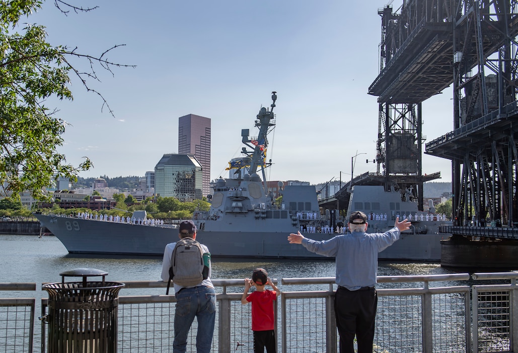 PORTLAND, OREGON (June 3, 2025) – A family waves as the Arleigh Burke-class guided missile destroyer USS Mustin (DDG 89) arrives for the annual Rose Festival during Portland Fleet Week in Portland, Oregon, June 3, 2025. Portland Fleet Week is a time-honored celebration of the sea services and provides an opportunity for the citizens of Oregon to meet Sailors, Marines and Coast Guardsmen, as well as witness firsthand the latest capabilities of today’s maritime services. (U.S. Navy photo by Mass Communication Specialist 2nd Class Gwendelyn L. Ohrazda)