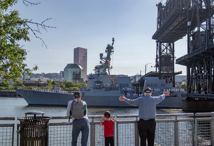 PORTLAND, OREGON (June 3, 2025) – A family waves as the Arleigh Burke-class guided missile destroyer USS Mustin (DDG 89) arrives for the annual Rose Festival during Portland Fleet Week in Portland, Oregon, June 3, 2025. Portland Fleet Week is a time-honored celebration of the sea services and provides an opportunity for the citizens of Oregon to meet Sailors, Marines and Coast Guardsmen, as well as witness firsthand the latest capabilities of today’s maritime services. (U.S. Navy photo by Mass Communication Specialist 2nd Class Gwendelyn L. Ohrazda)