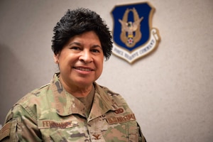 Col. Sylvia Fernandez smiles for a portrait with the Air Force Reserve crest on the wall in background