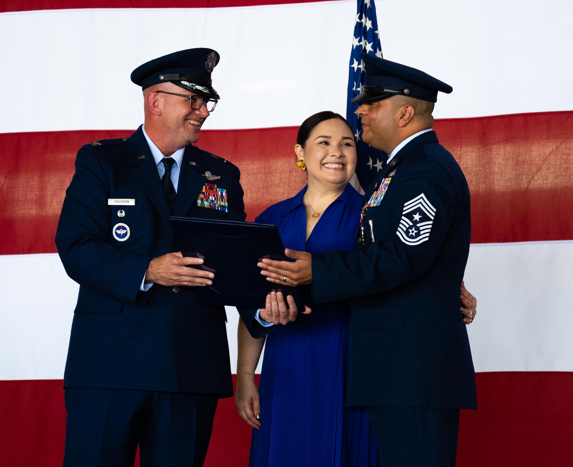 U.S. Air Force Col. Kevin Davidson, left, Africa Command Washington Liaison Office, director, presents a Certificate of Appreciation, to Esmerelda Largaespada, center, and Chief Master Sgt. Lester Largaespada, right, 47th Flying Training Wing command chief, at Laughlin Air Force Base, Texas, June 6, 2025. The retirement ceremony celebrated the 29 year career of Largaespada. (U.S. Air Force photo by Staff Sgt. Nicholas Larsen)