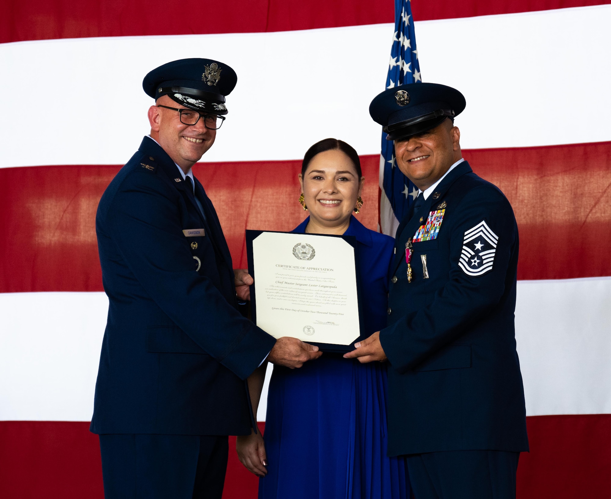 U.S. Air Force Col. Kevin Davidson, left, Africa Command Washington Liaison Office, director, presents a Certificate of Appreciation, to Esmerelda Largaespada, center, and Chief Master Sgt. Lester Largaespada, right, 47th Flying Training Wing command chief, at Laughlin Air Force Base, Texas, June 6, 2025. The retirement ceremony celebrated the 29 year career of Largaespada. (U.S. Air Force photo by Staff Sgt. Nicholas Larsen)