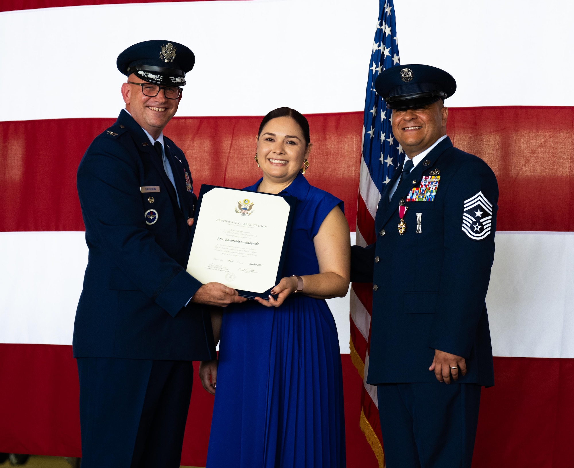 U.S. Air Force Col. Kevin Davidson, left, Africa Command Washington Liaison Office, director, presents a Certificate of Appreciation, to Esmerelda Largaespada, center, and Chief Master Sgt. Lester Largaespada, right, 47th Flying Training Wing command chief, at Laughlin Air Force Base, Texas, June 6, 2025. The retirement ceremony celebrated the 29 year career of Largaespada. (U.S. Air Force photo by Staff Sgt. Nicholas Larsen)