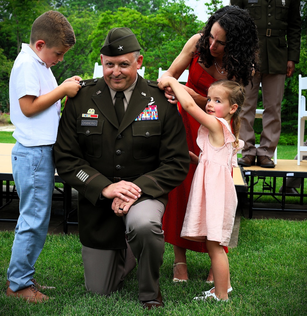 Illinois Army National Guard Maj. Gen. Justin Osberg watches as his son, 7-year-old Evan, and daughter, 4-year-old Juliana, pin his second star on his uniform with help from his spouse, Jessica
