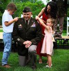 Illinois Army National Guard Maj. Gen. Justin Osberg watches as his son, 7-year-old Evan, and daughter, 4-year-old Juliana, pin his second star on his uniform with help from his spouse, Jessica