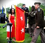Illinois Army National Guard Maj. Gen. Justin Osberg and his spouse, Jessica, unfurl his Two-Star General Officer Flag during Osberg’s promotion ceremony
