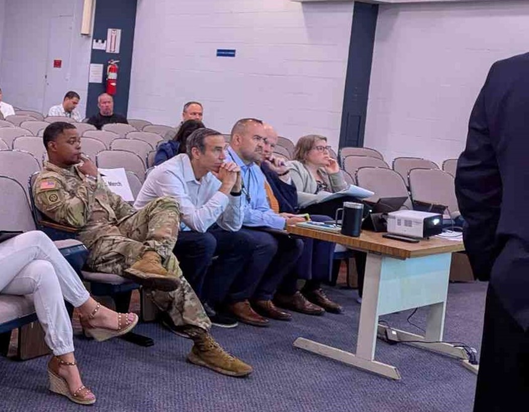 civilian and uniformed men and women sit in auditorium