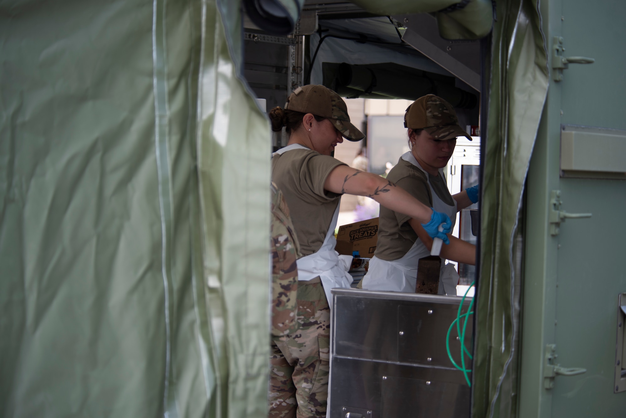 Two 155th Air Refueling Wing services technicians prepare food for their fellow Airmen using a single pallet expedition kitchen during a Combat Readiness Exercise, June 6, 2025, at the Nebraska National Guard air base in Lincoln, Nebraska.