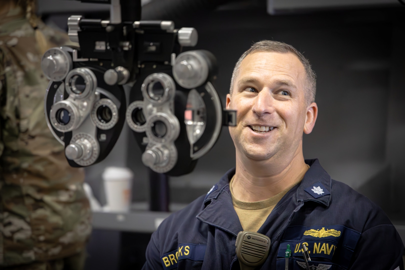 Service member stands behind optometry equipment