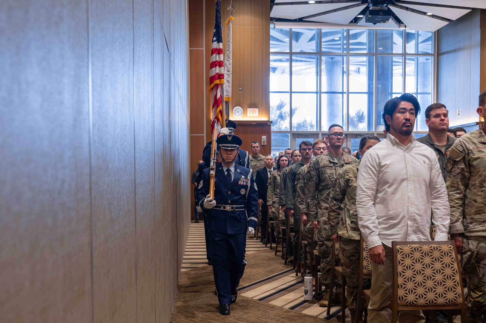 A service member is walking down an isle with a flag.