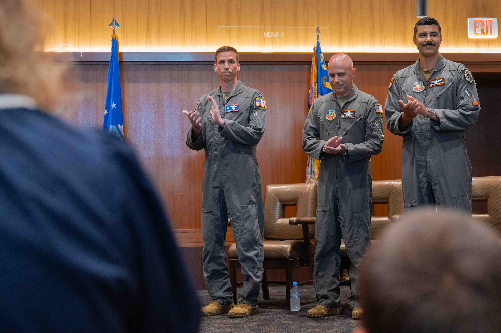 Three service members are clapping in the photo.