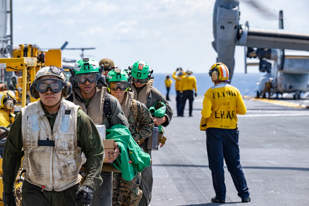 Marines assigned to the 31st Marine Expeditionary Unit (MEU) depart an MV-22B Osprey tiltrotor aircraft on the flight deck of the forward-deployed amphibious assault ship USS America (LHA 6) while conducting flight operations in the Philippine Sea, May 27.