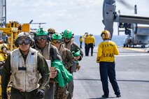 Marines assigned to the 31st Marine Expeditionary Unit (MEU) depart an MV-22B Osprey tiltrotor aircraft on the flight deck of the forward-deployed amphibious assault ship USS America (LHA 6) while conducting flight operations in the Philippine Sea, May 27.