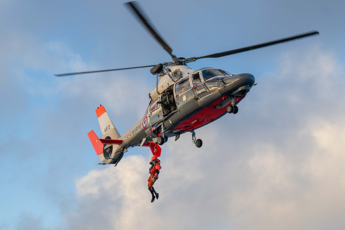 A Marine Nationale rescue swimmer descends from a French Navy Flottille 35F AS365 Dauphin helicopter during a joint training exercise between the French Navy and U.S. Coast Guard Cutter Harriet Lane (WMEC 903) on May 31, 2025 off the Coast of Tahiti, French Polynesia.
